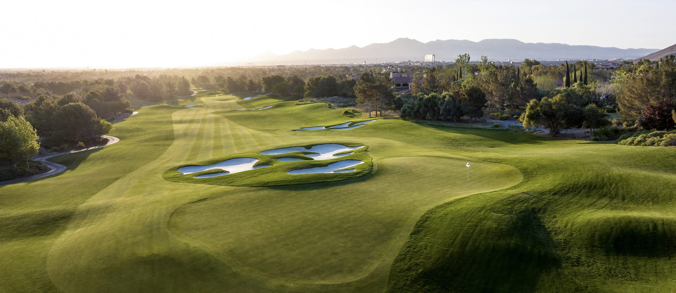 Fairway and green at sunrise with bunkering and mountains beyond